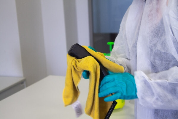 adult in protective clothing cleans an object in an office