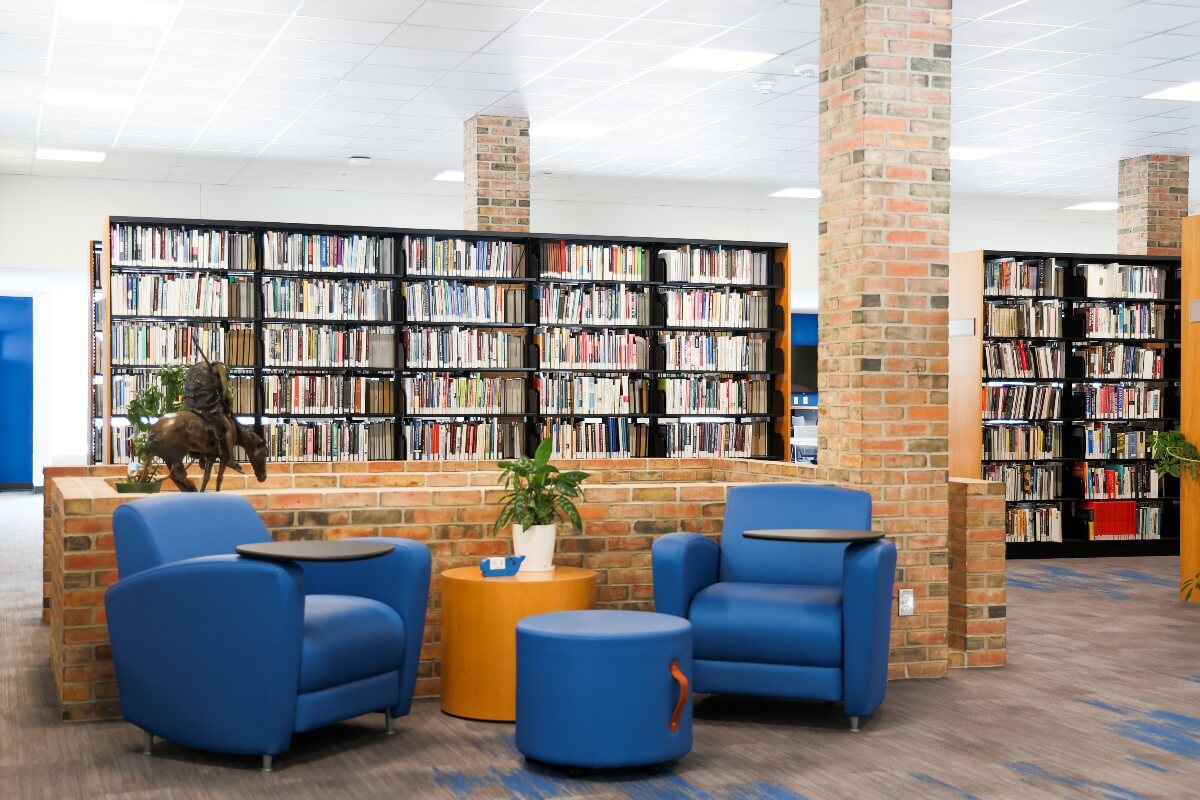 blue chairs in a library sitting area with bookshelves behind
